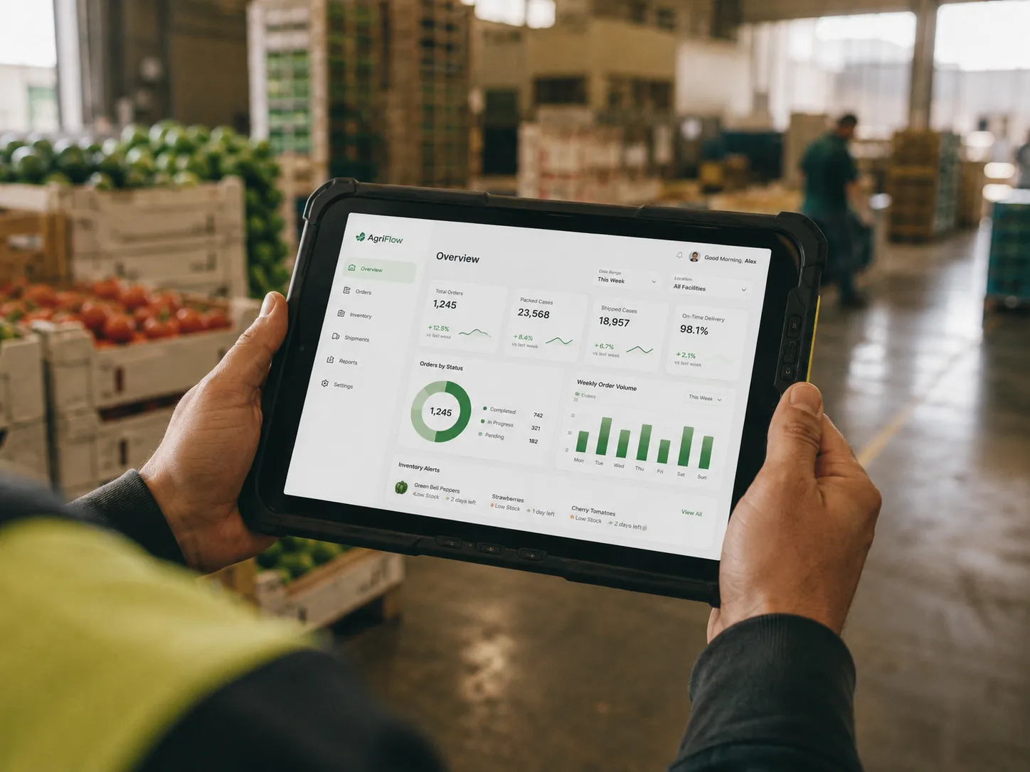 A worker reviewing a produce operations dashboard on a rugged tablet inside a packing warehouse